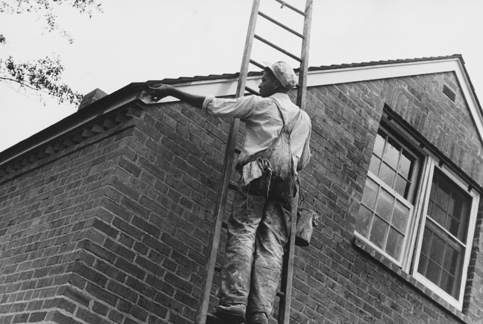 Man painting the side of a brick house