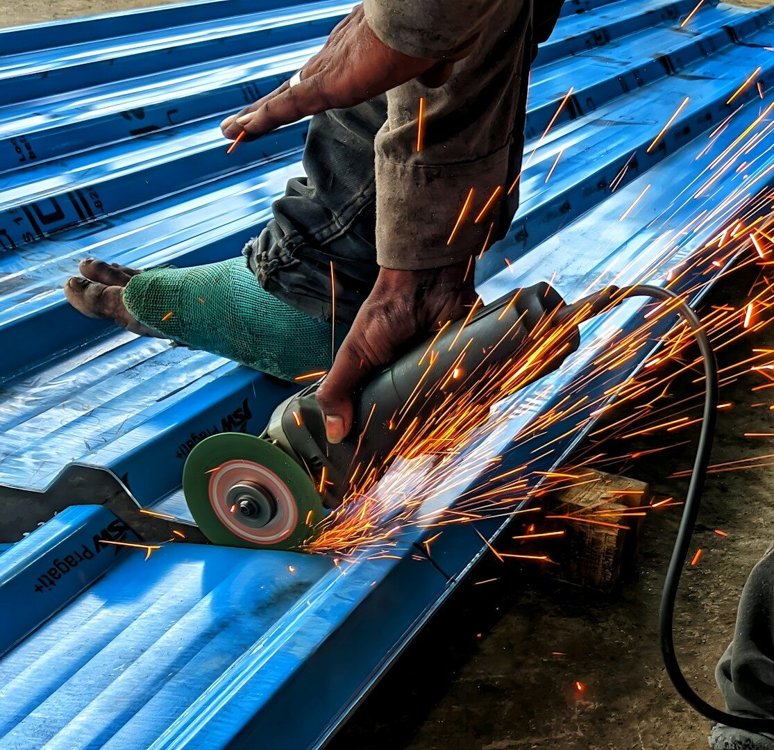 a man grinds a piece of metal with a grinder
