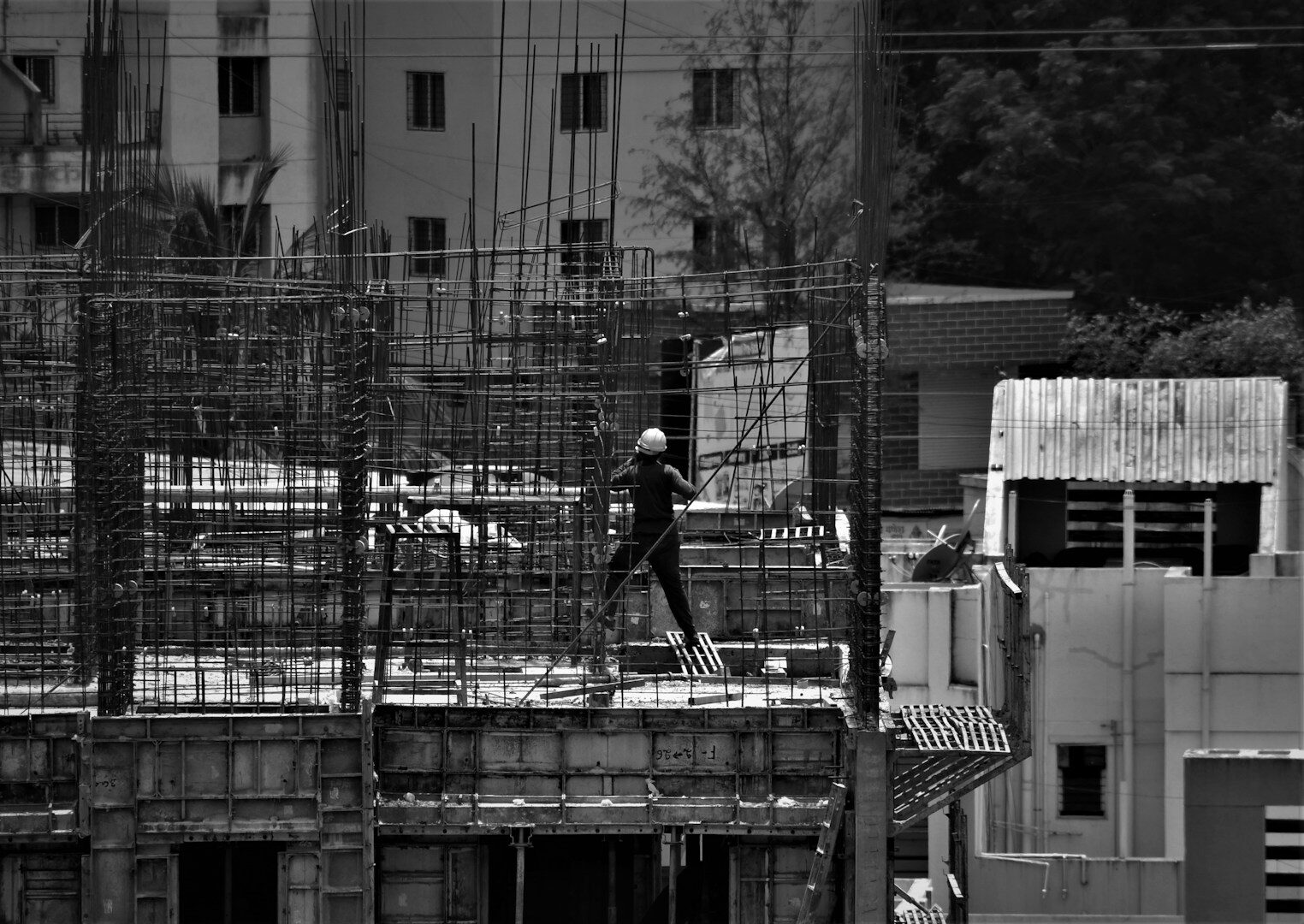 grayscale photo of man in black jacket and pants standing on building